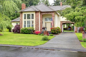 Beautiful curb appeal. Large brick house with siding trim and tile roof. View of entrance hight ceiling porch and driveway with arch