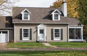 Gray Cape Cod style house with screened-in side porch.